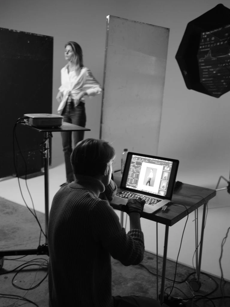 Small game studio workspace with designers at dual-monitor desks, warm lighting